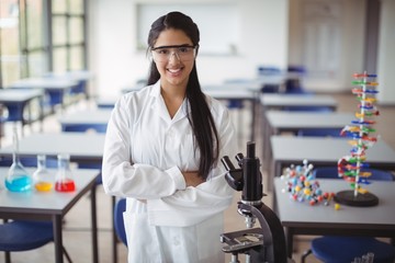 Schoolgirl in lab coat standing with arms crossed 