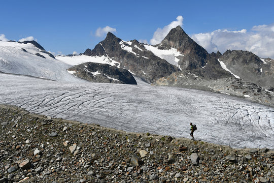 Trekker walking on moraine close to Rutor (or Ruitor) glacier, (close to Deffeyes refuge),(Grand Assaly summit on background),La Thuile valley, Aosta Valley, Italy, Europe