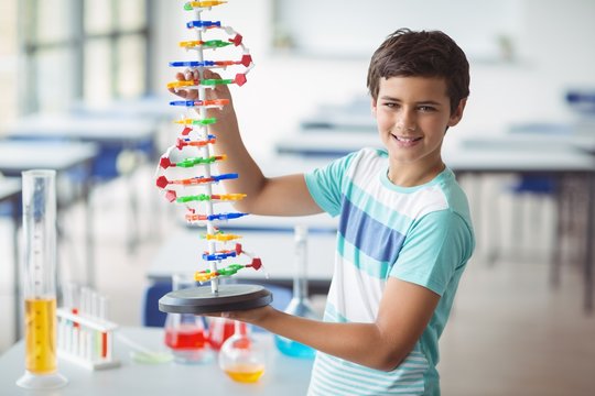 Portrait of schoolboy experimenting molecule model in laboratory