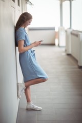 Fototapeta na wymiar Schoolgirl using mobile phone in corridor