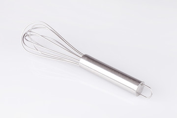 Stainless steel whisk on white surface. Isolated on white background.