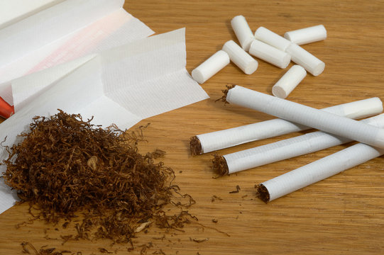 Homemade cigarettes, filters and tobacco paper on wooden background