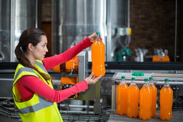 Female factory worker examining a bottle of juice