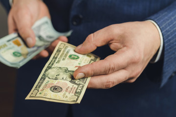Male hand gives one ten dollars banknote, close-up view, business and finance concept.
