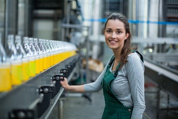 Female factory worker standing near production line - Powered by Adobe