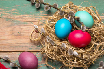 Easter background with eggs, nest and catkins on old wooden background. Copy space