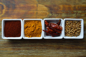 Spices in white dishes on wood background