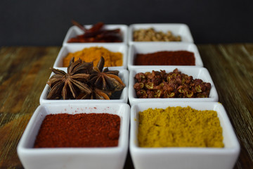 Spices in white dishes on wood background