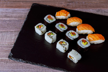 Large set of japanese rolls on a black plate