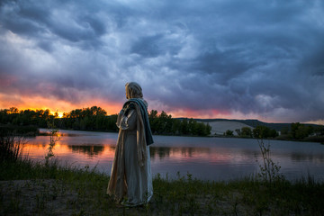 Jesus Christ next to a sun setting on the lake
