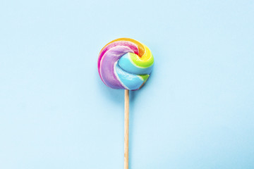 rainbow colored lollipop isolated on blue background. copy space