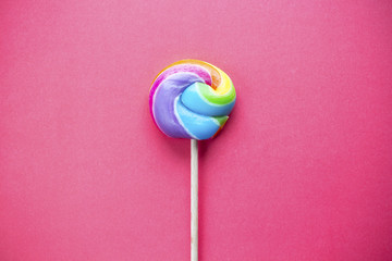 rainbow colored lollipop isolated on pink background. copy space