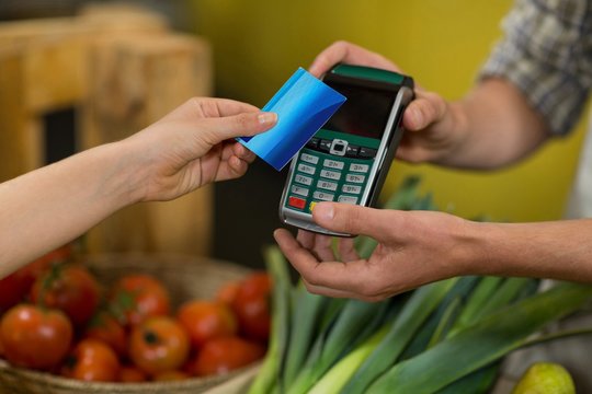 Woman making a payment by using NFC technology in the grocery store
