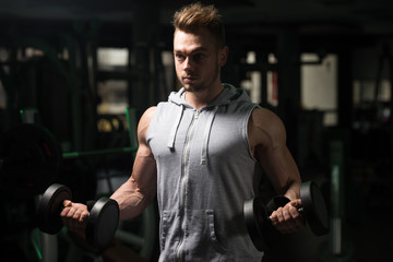 Bodybuilder Exercising Biceps With Dumbbells In Gym