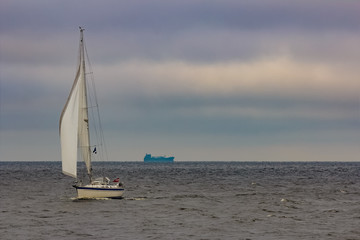 White sailboat traveling in Baltic sea in cloudy day