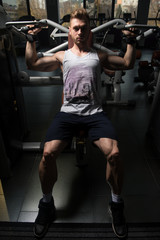 Fototapeta na wymiar Bodybuilder Exercising Shoulders On Machine