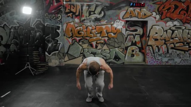 Man performing a front flip backflip acrobatics in crossfit center, jump training with power athlete