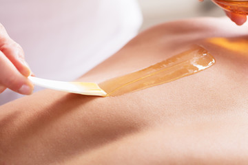 Woman Waxing Man's Chest With Wax Strip