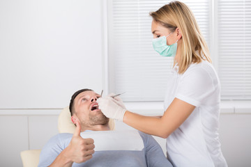 Man Showing Thumb Up Sign While Having Dental Checkup