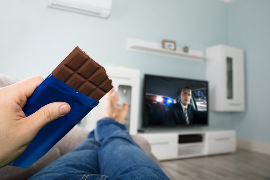 Person Enjoying Chocolate While Watching Television