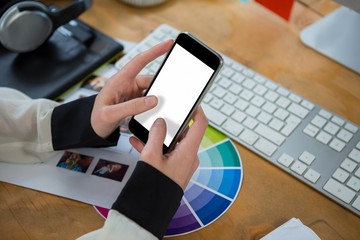 Female graphic designer using mobile phone at desk - Powered by Adobe