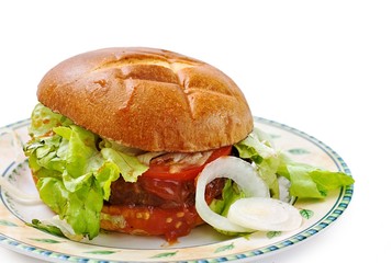 Homemade beef burger with iceburg lettuce, sliced tomato and tomato relish on ceramic plate