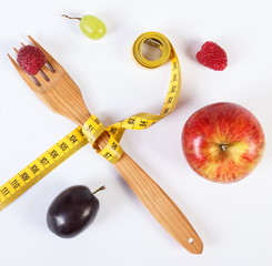 Fresh ripe fruits and fork with centimeter on white background