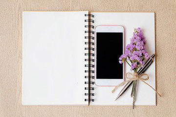 Mobile phone and notebook on wooden table and bouquet flower. Copy space .