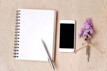 Mobile phone with gift box and flower on woodden background. Flat lay, top view workspace