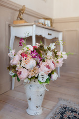 A beautiful spring bouquet in pastel colors stands in a vase on the floor