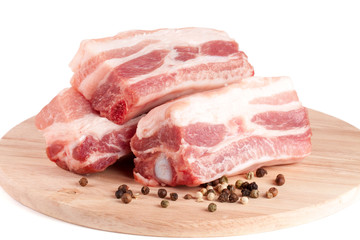 pieces of pork with peppercorn on a cutting board isolated on white background