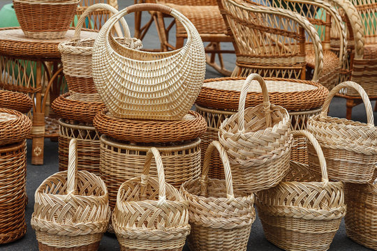 A variety of braided vines items are on the ground. Baskets are in the foreground. Wicker chairs and tables at a village fair. Traditional Belarusian Handicrafts.