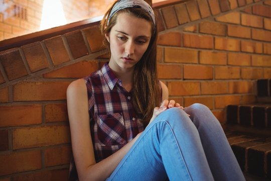 Sad schoolgirl sitting alone on staircase