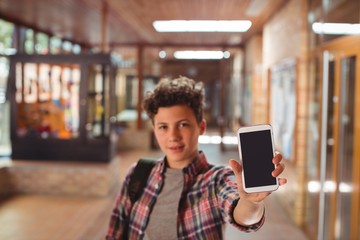 Schoolboy standing showing mobile phone