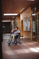 Obraz premium Disabled schoolboy on wheelchair in corridor at school