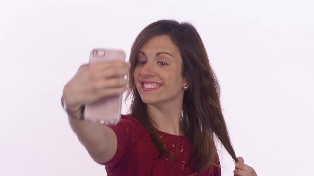 A woman takes selfies and makes the duck face. Close-up shot on white background.