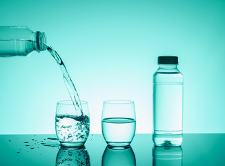 Bottle with creative splashing water in the glass