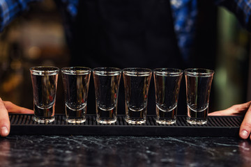 Barman at work,Barman pouring hard spirit into glasses in detail,Bartender is pouring tequila into...