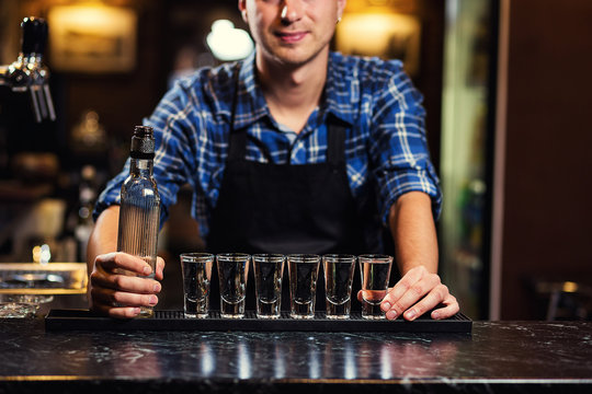 Barman at work,Barman pouring hard spirit into glasses in detail,Bartender is pouring tequila into glass,preparing cocktails,service concept