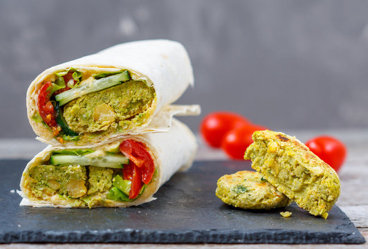 Green falafel with hummus and vegetables in pita bread on a slate and dark background. Love for a healthy vegan food concept