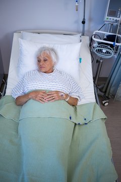 Thoughtful senior patient lying on bed