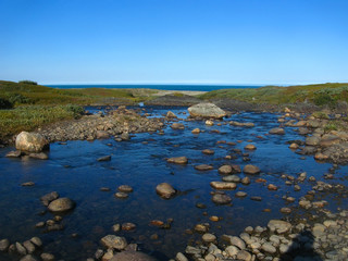 Background blurred view landscape shallow river flowing over the plateau and flowing into the Barents Sea on the Rybachiy peninsula, Murmansk region
