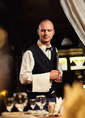 Waiter served table in the restaurant before the feast,Waiter in uniform waiting an order,Waiter with a white towel on his hand,Confident waiter