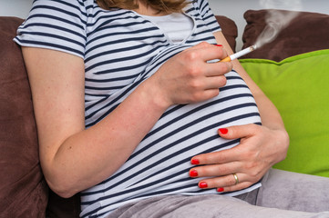 Pregnant woman smoking cigarette at home