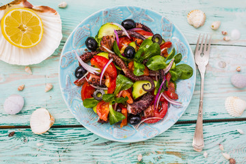 Mediterranean salad with grilled octopus on wooden background.