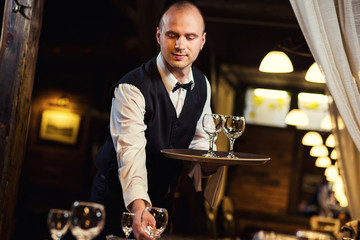 Waiter served table in the restaurant before the feast,Waiter in uniform waiting an order,Waiter with a white towel on his hand,Confident waiter
