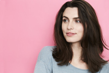 Fototapeta premium Brown haired beauty looking away in pink studio