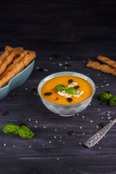 Pumpkin and carrot cream soup on a wooden background