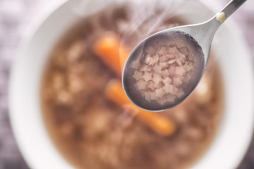 traditional hot beef roth with vegetable, top view of hot soup with carrot and pasta