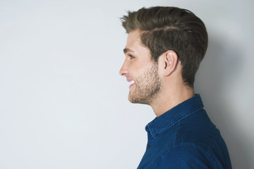 Handsome profile portrait of young smiled man. Attractive man side look isolated on grey background